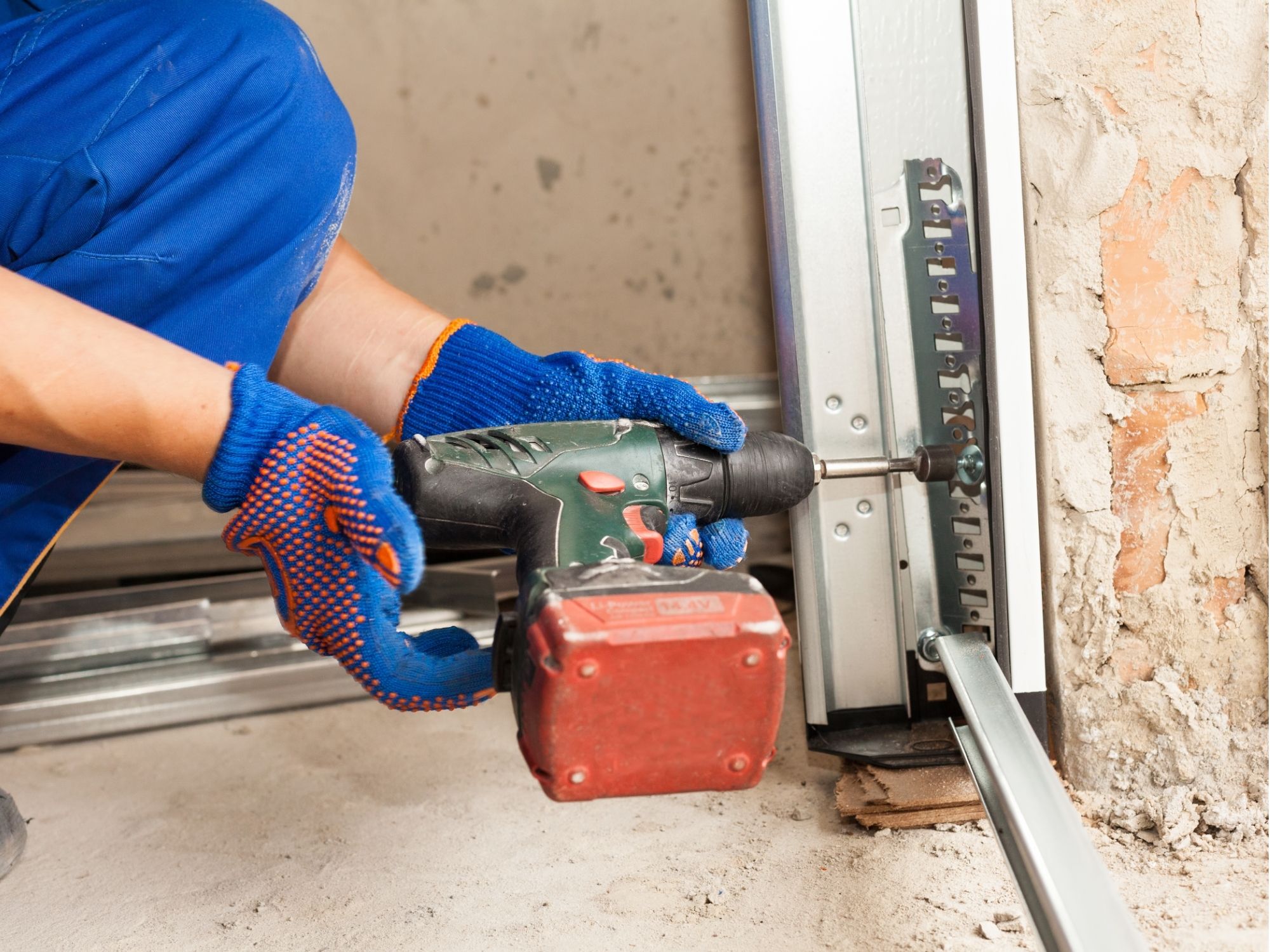 Garage door track hardware being repaired with a drill
